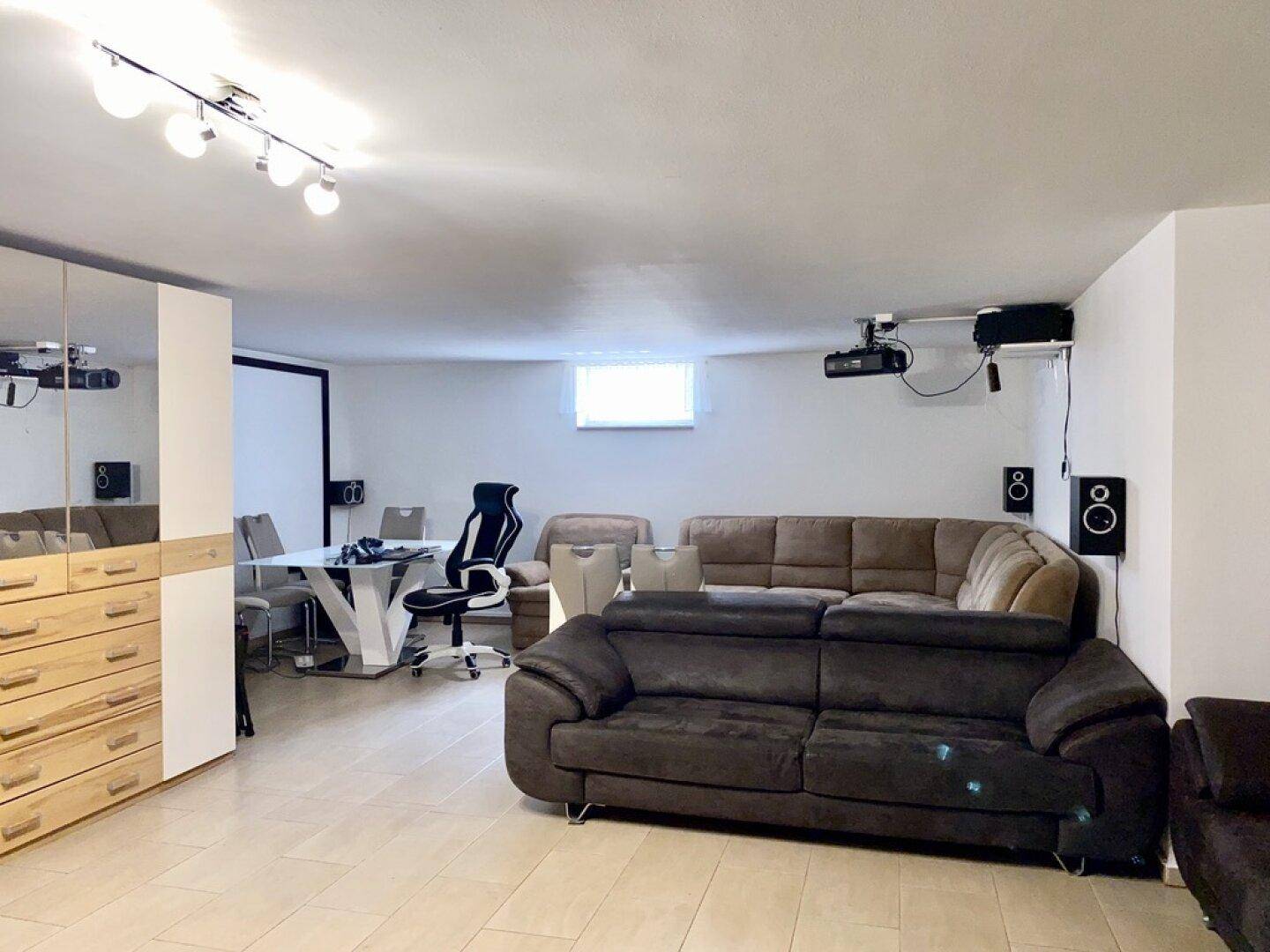 Gemütlicher Medienraum im Untergeschoss mit Sofas, Projektor und Leinwand für Unterhaltung.