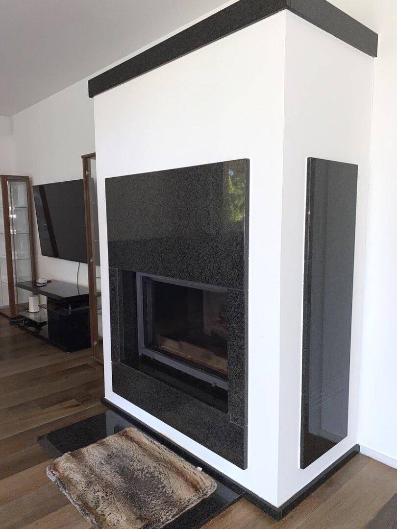 Moderner Kamin mit schwarzer Granitverkleidung als Blickfang im Wohnzimmer.
