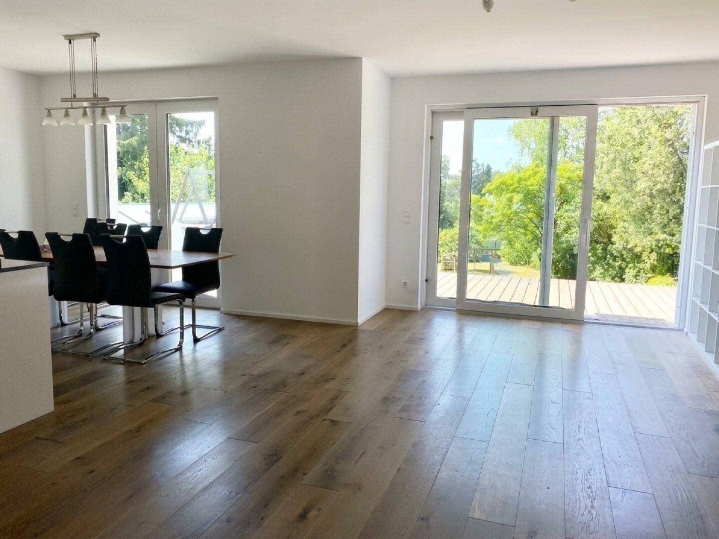 Heller Wohn- und Essbereich mit Holzboden und großen Schiebetüren zur Terrasse.