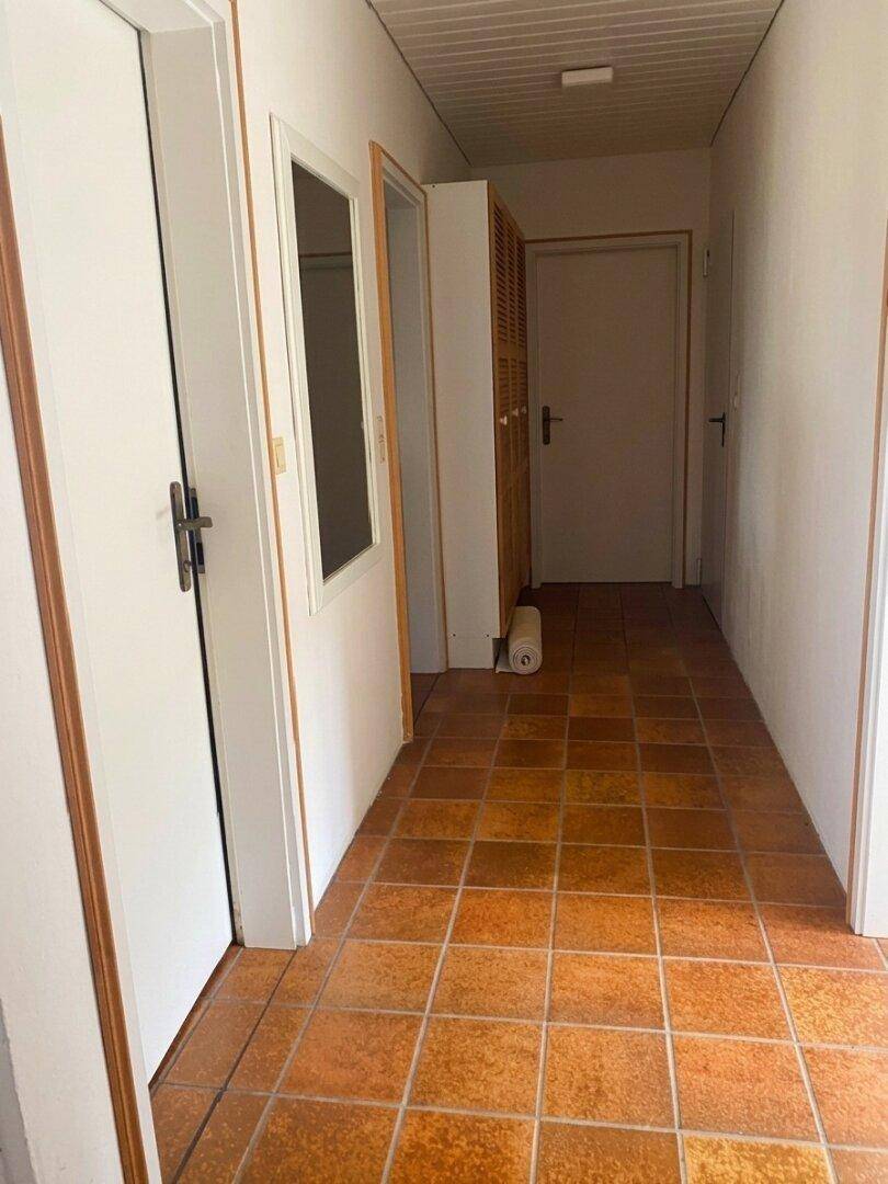 Langer Flur mit Terrakottafliesen und mehreren Türen, der verschiedene Räume verbindet.