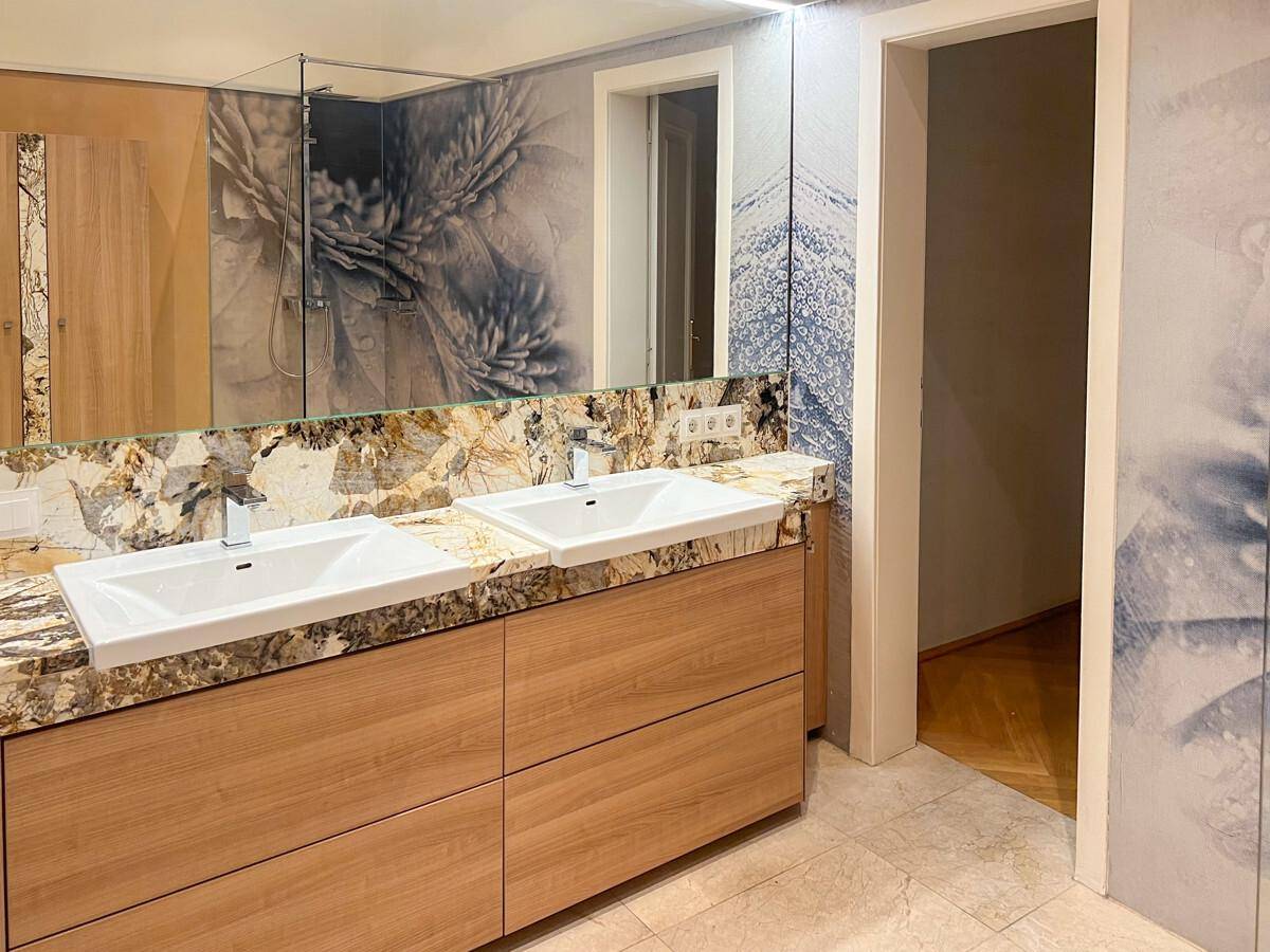 Modernes Badezimmer mit Doppelwaschbecken, Granitplatte und dekorativer Wandgestaltung.