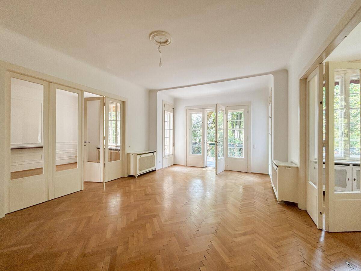 Helles Wohnzimmer mit klassischem Fischgrätparkett und eleganten Flügeltüren.
