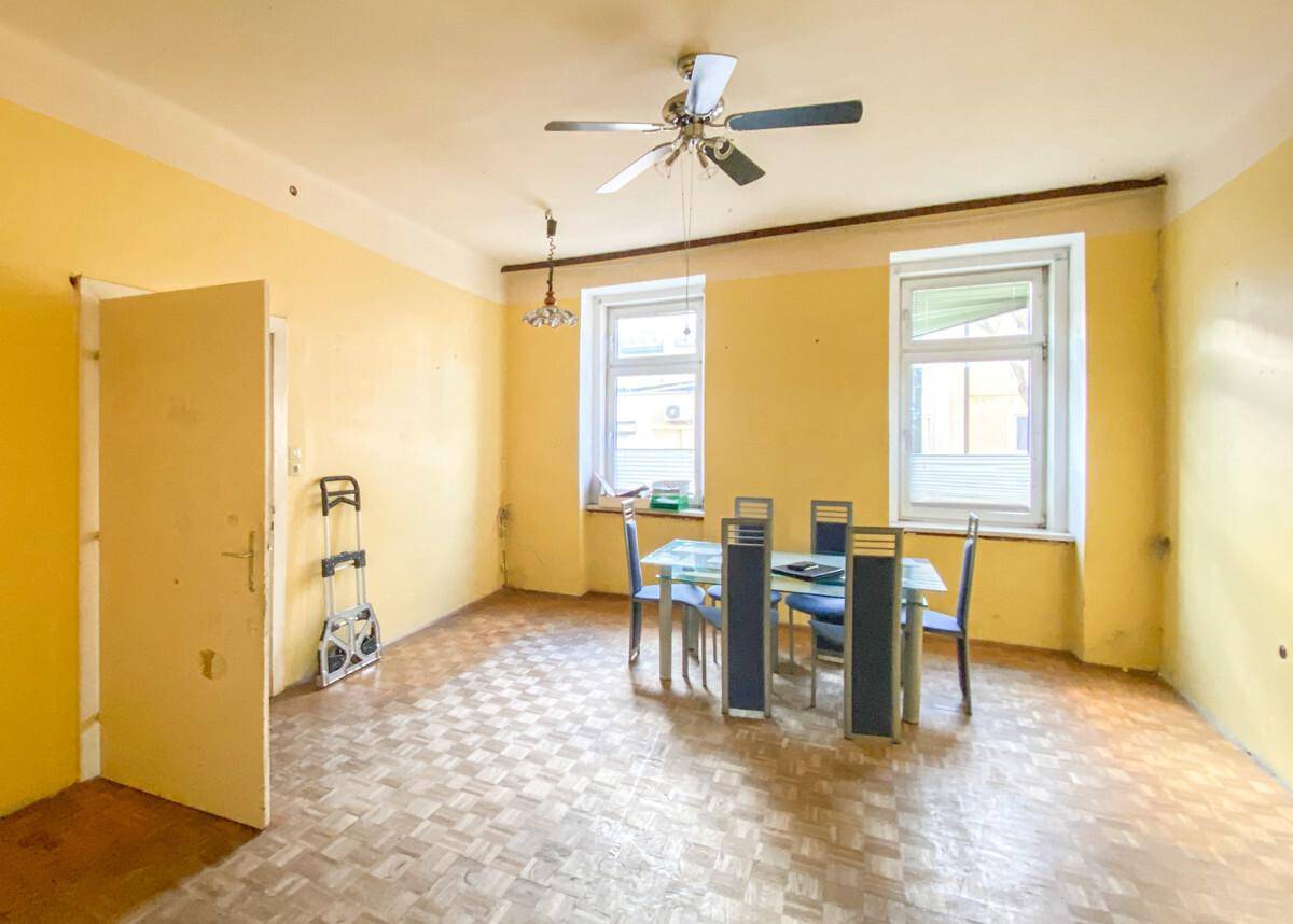 Heller Essbereich mit gelben Wänden, Parkettboden, Deckenventilator und Esstisch.