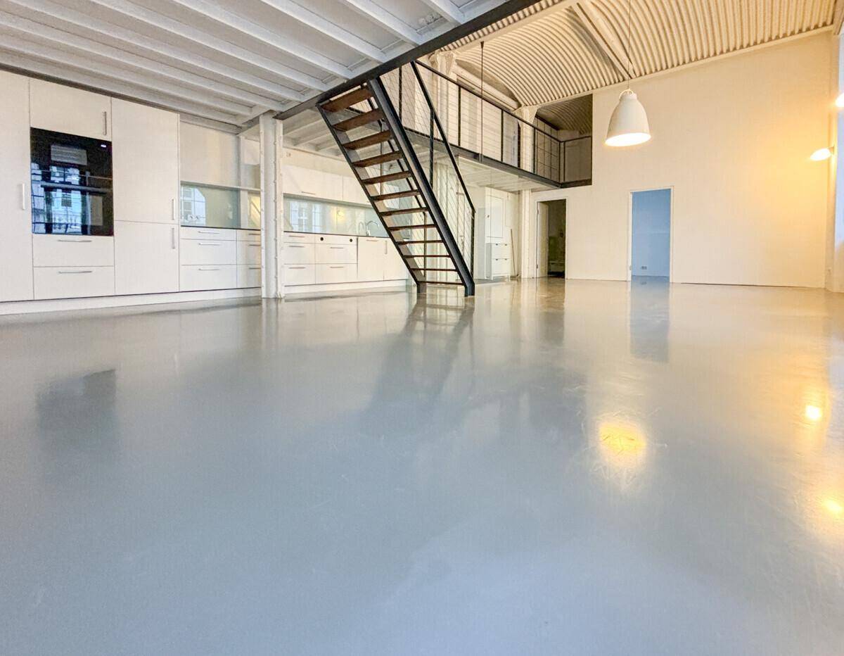 Geräumiger Wohnbereich mit integrierter moderner Küche, Galerie und industrieller Treppe.