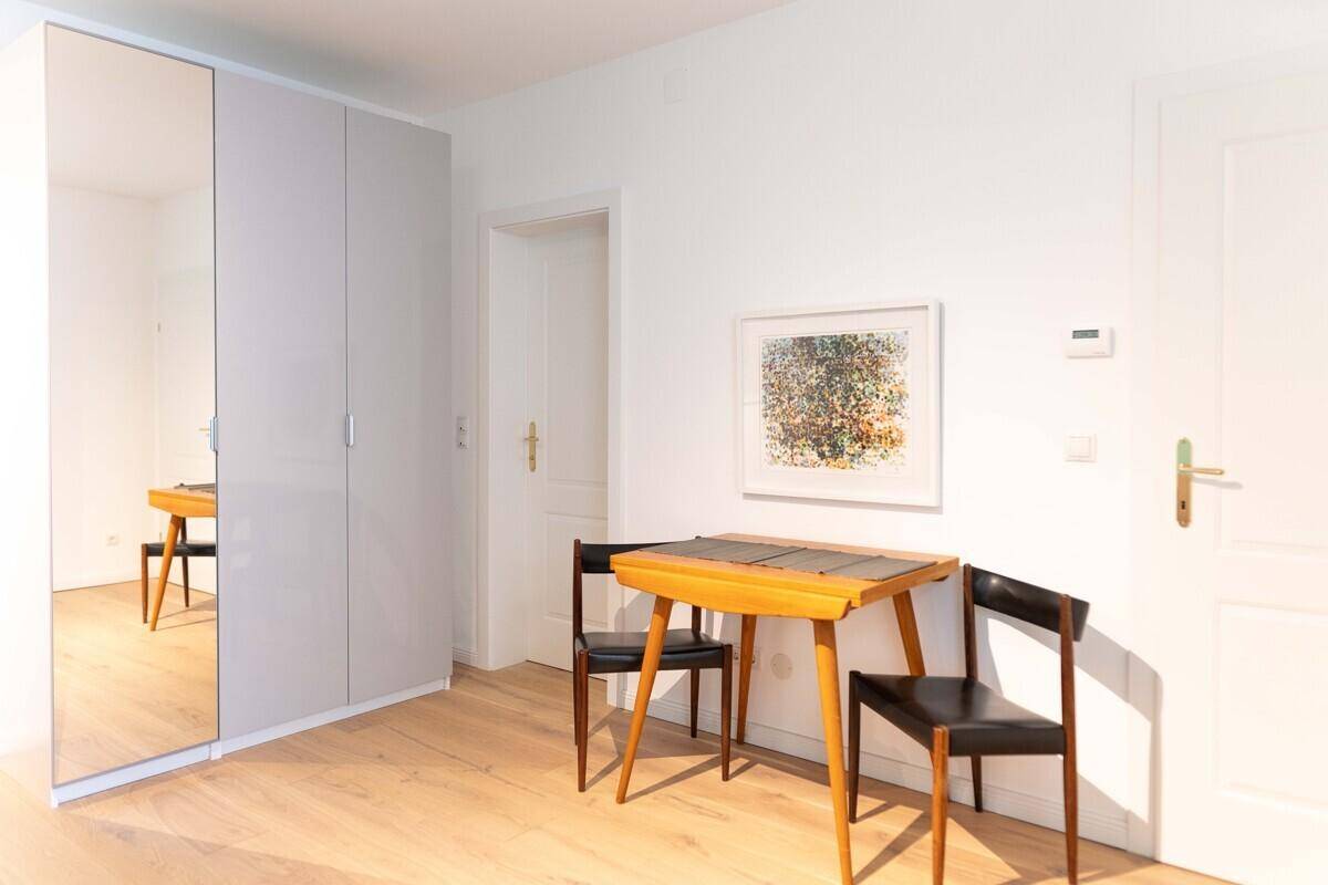 Heller Flur mit Spiegelschrank, Holzboden und kleinem Esstisch.