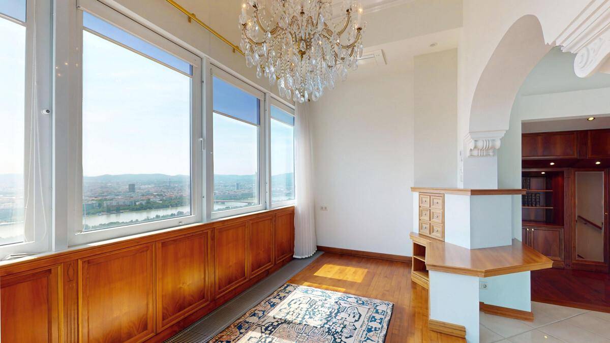 Heller Wohnbereich mit Holztäfelung, Kronleuchter und weitem Blick über die Stadt.