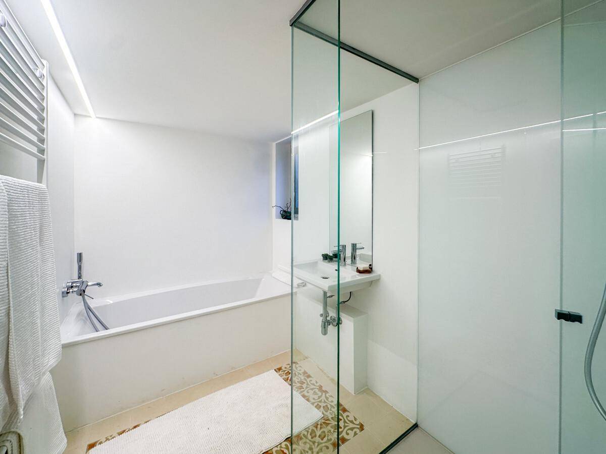 Modernes Badezimmer mit Badewanne, Duschbereich und beheiztem Handtuchhalter.