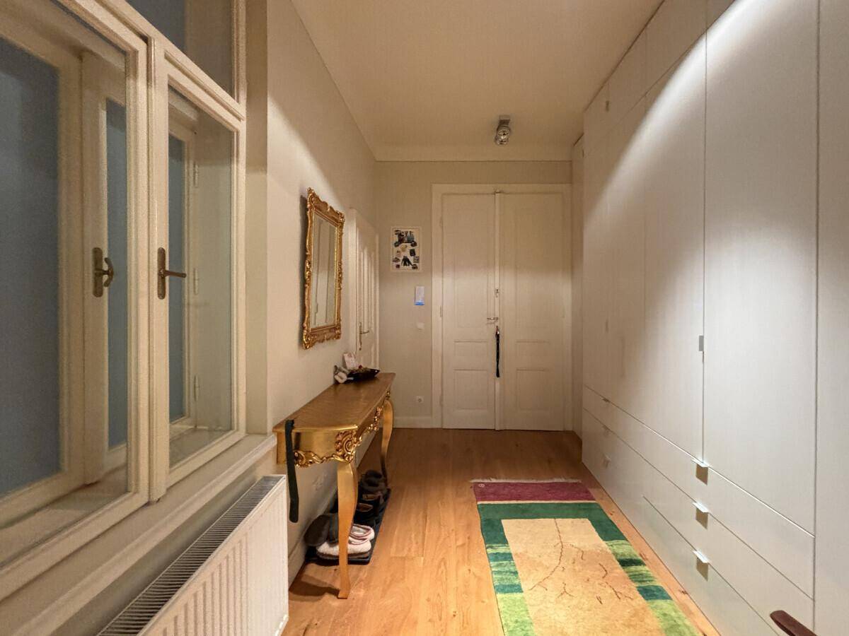 Langer Flur mit Einbauschränken, Holzboden und dekorativem Spiegel.