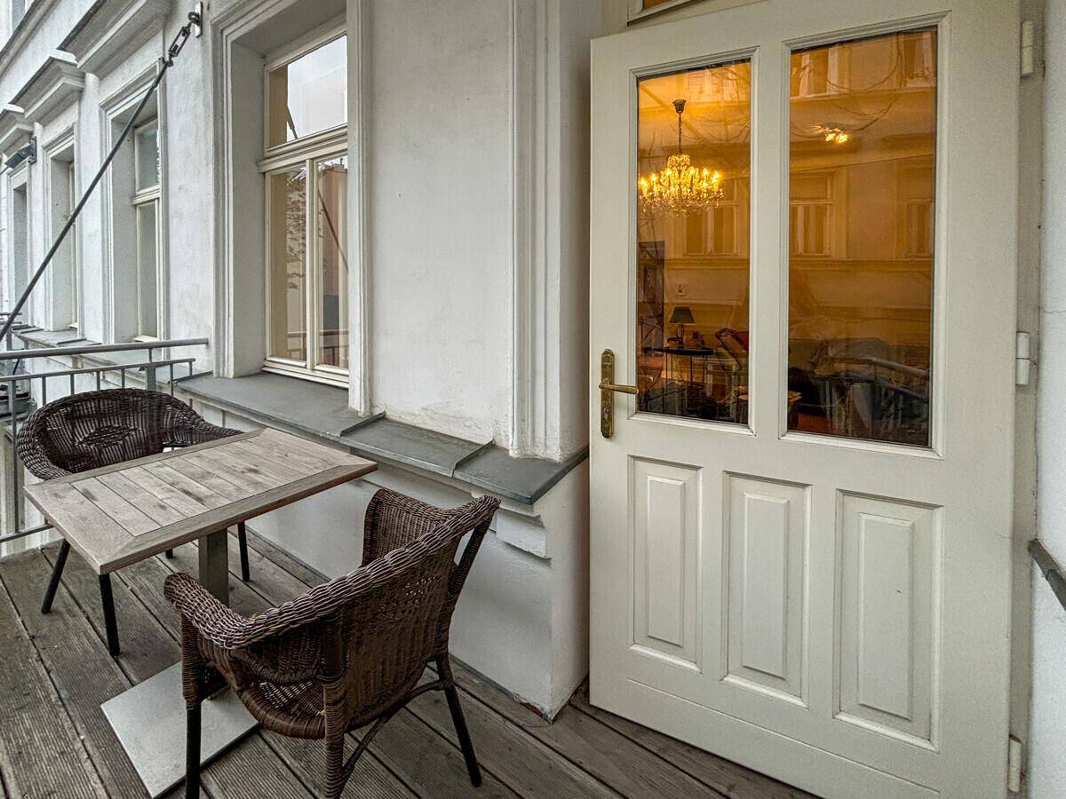 Kleiner Balkon mit Holzboden und Sitzgelegenheiten, zugänglich vom Innenbereich.