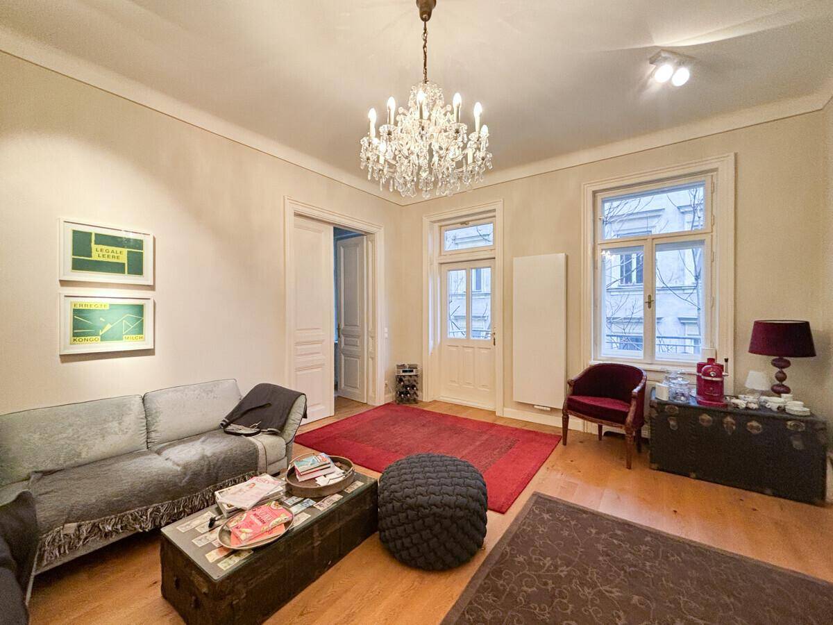 Geräumiges Wohnzimmer mit Holzboden, Kronleuchter und Blick auf die Straße.