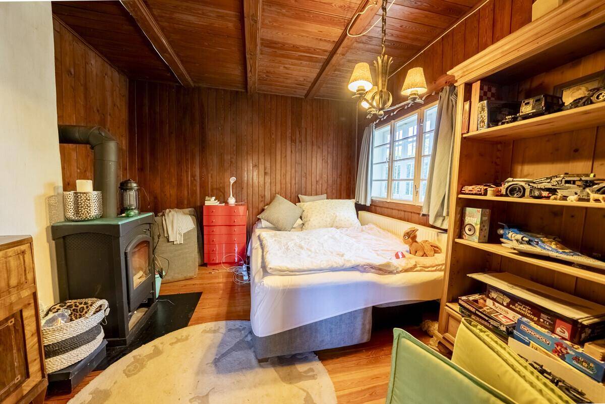 Gemütliches Zimmer mit Holztäfelung, einem Bett und einem traditionellen Holzofen für warme Abende.