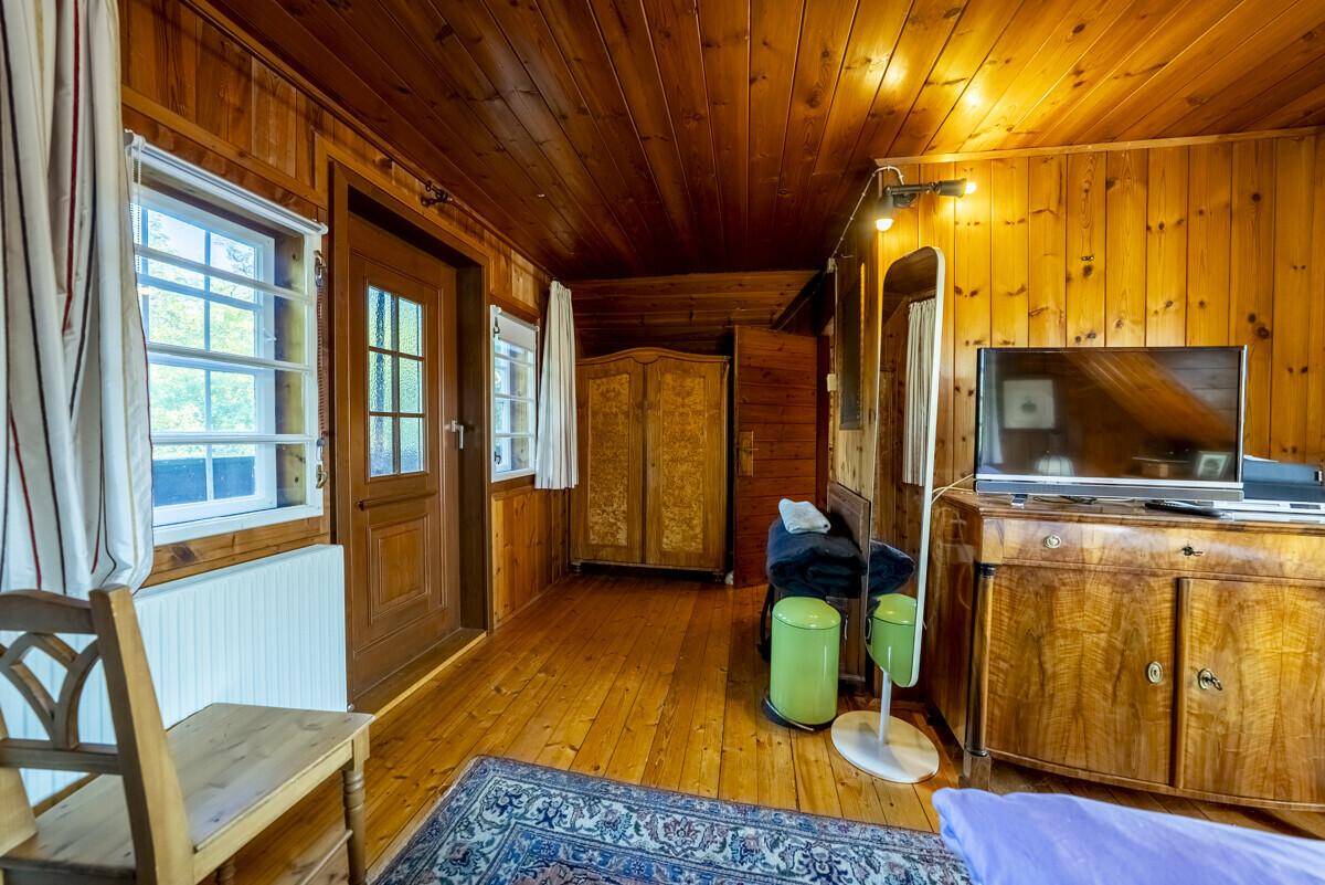Gemütliches Schlafzimmer mit Holztäfelung an Wänden und Decke, traditionellem Mobiliar und Teppich.