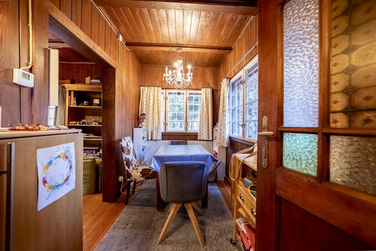 Essbereich mit Holzwänden und -decke, einem Esstisch und Fenstern, die viel Tageslicht hereinlassen.