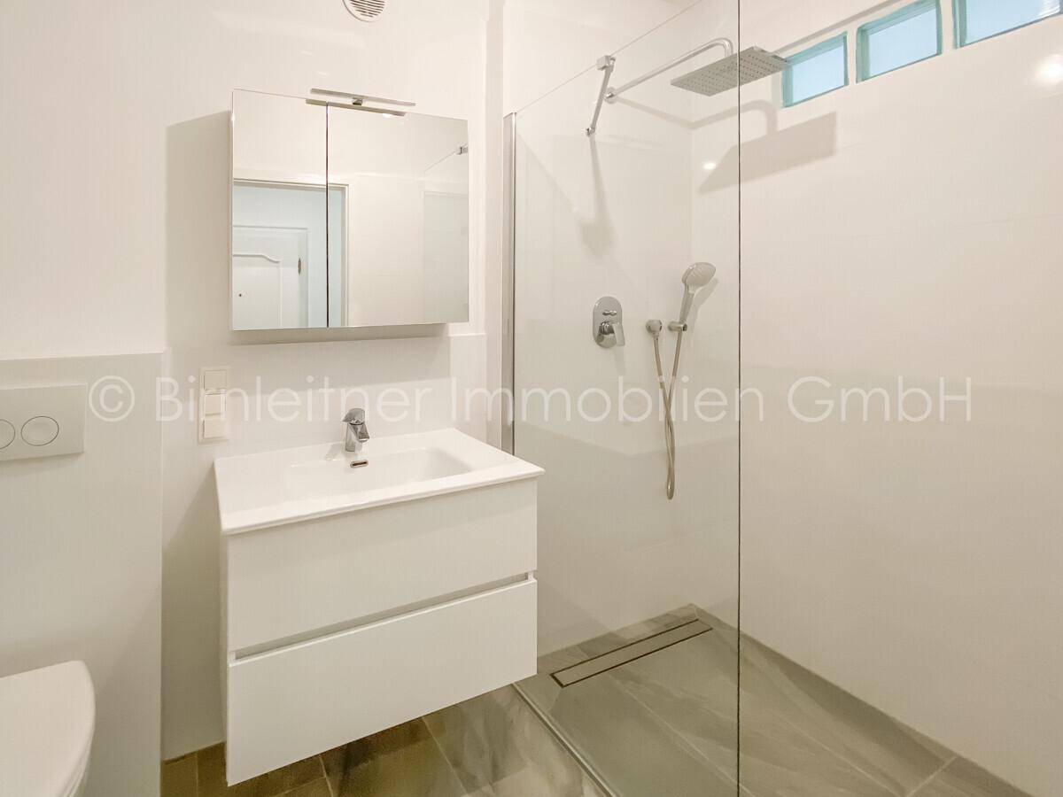 Modernes Badezimmer mit begehbarer Dusche, Einzelwaschbecken und Spiegelschrank.