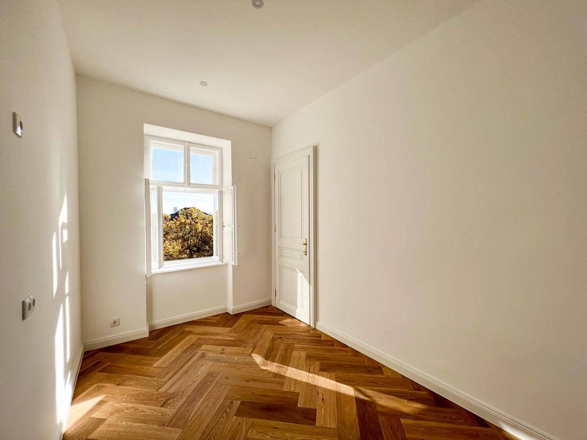 Gemütliches Zimmer mit Fischgrätparkett, einem Fenster und viel natürlichem Lichteinfall.