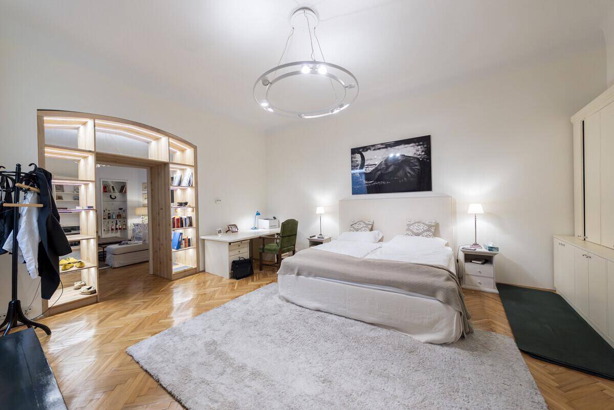 Geräumiges Schlafzimmer mit Parkettboden, großem Bett und offenem Zugang zu einem weiteren Raum.