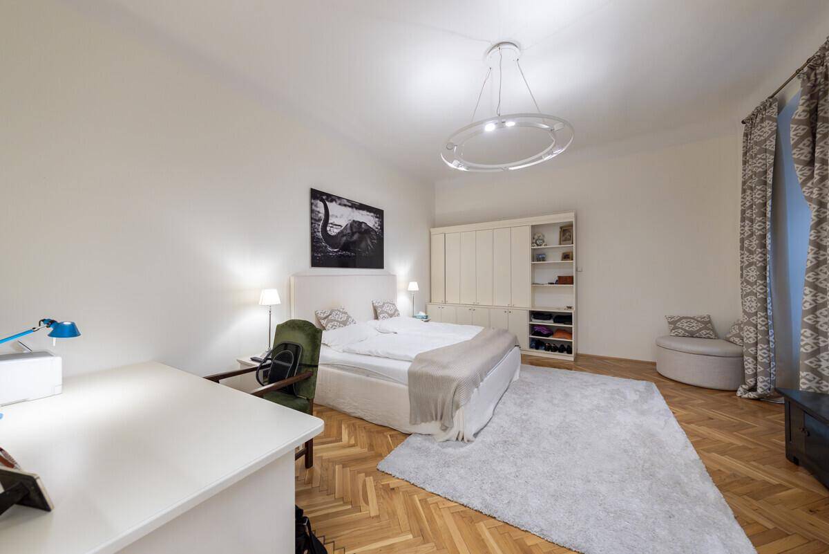 Modernes Schlafzimmer mit Parkettboden, großem Bett und einem Schreibtisch am Fenster.