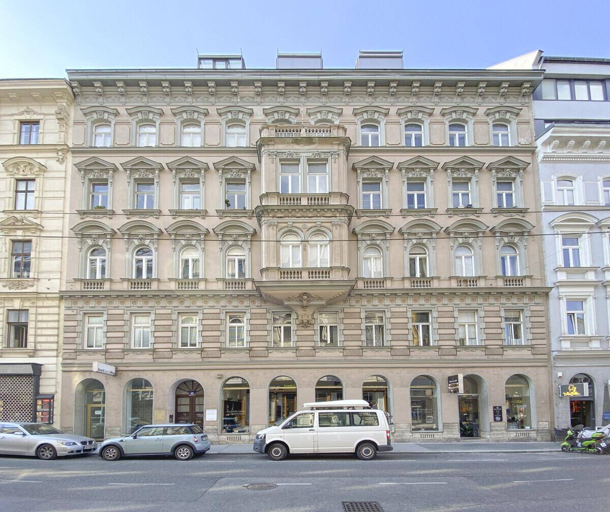Historische Fassade eines eleganten Wohngebäudes mit reich verzierten Fenstern und Balkonen.