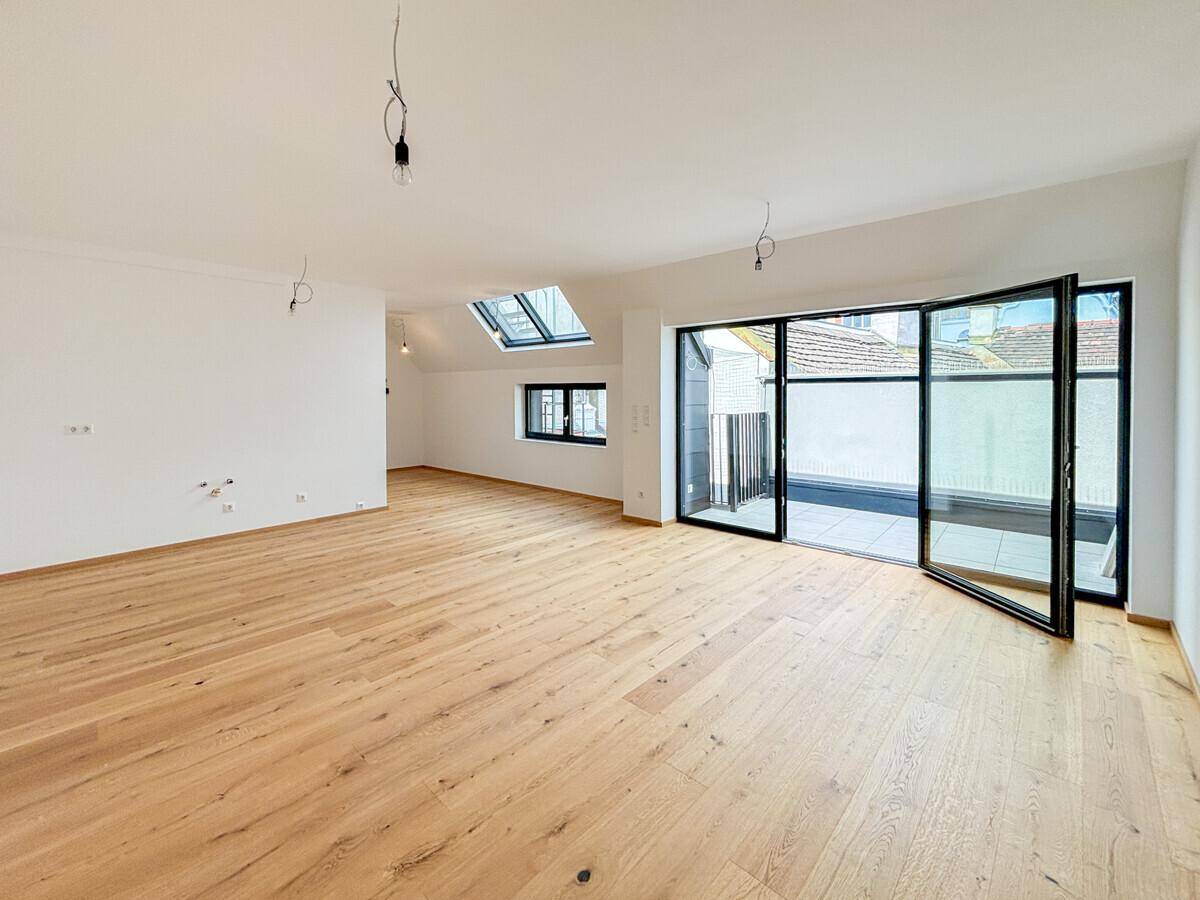 Geräumiges, helles Wohnzimmer mit Holzboden, Dachfenstern und Zugang zur Terrasse.