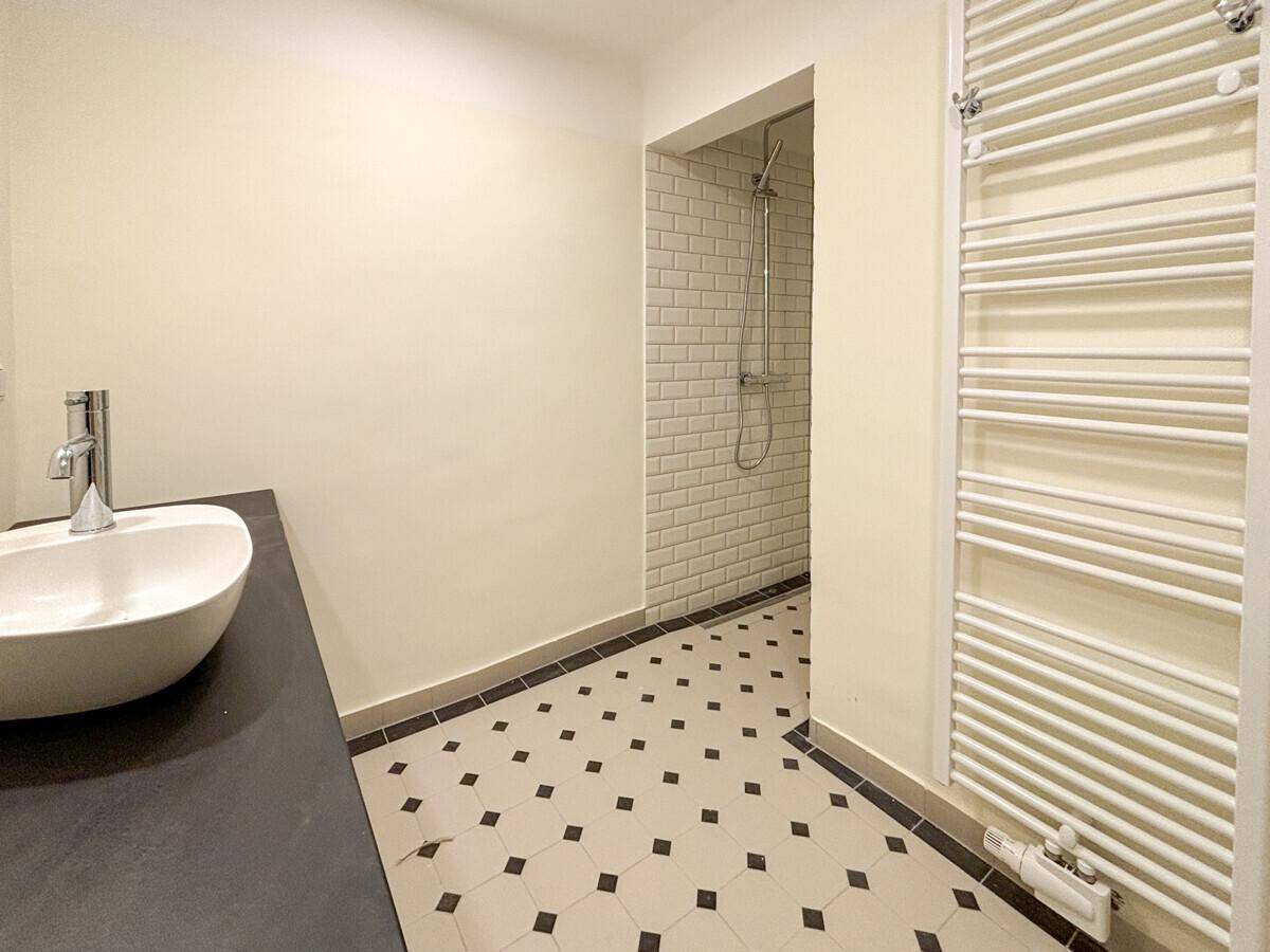 Modernes Badezimmer mit begehbarer Dusche, stilvollen Fliesen und einem beheizten Handtuchhalter.