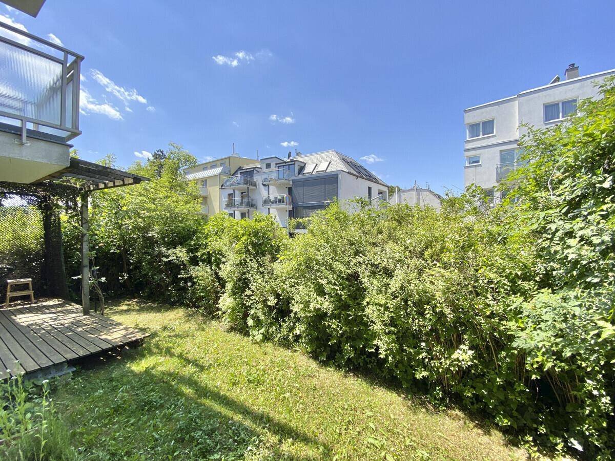 Weitläufiger Gartenbereich mit viel Grün und Blick auf die umliegenden Wohngebäude.