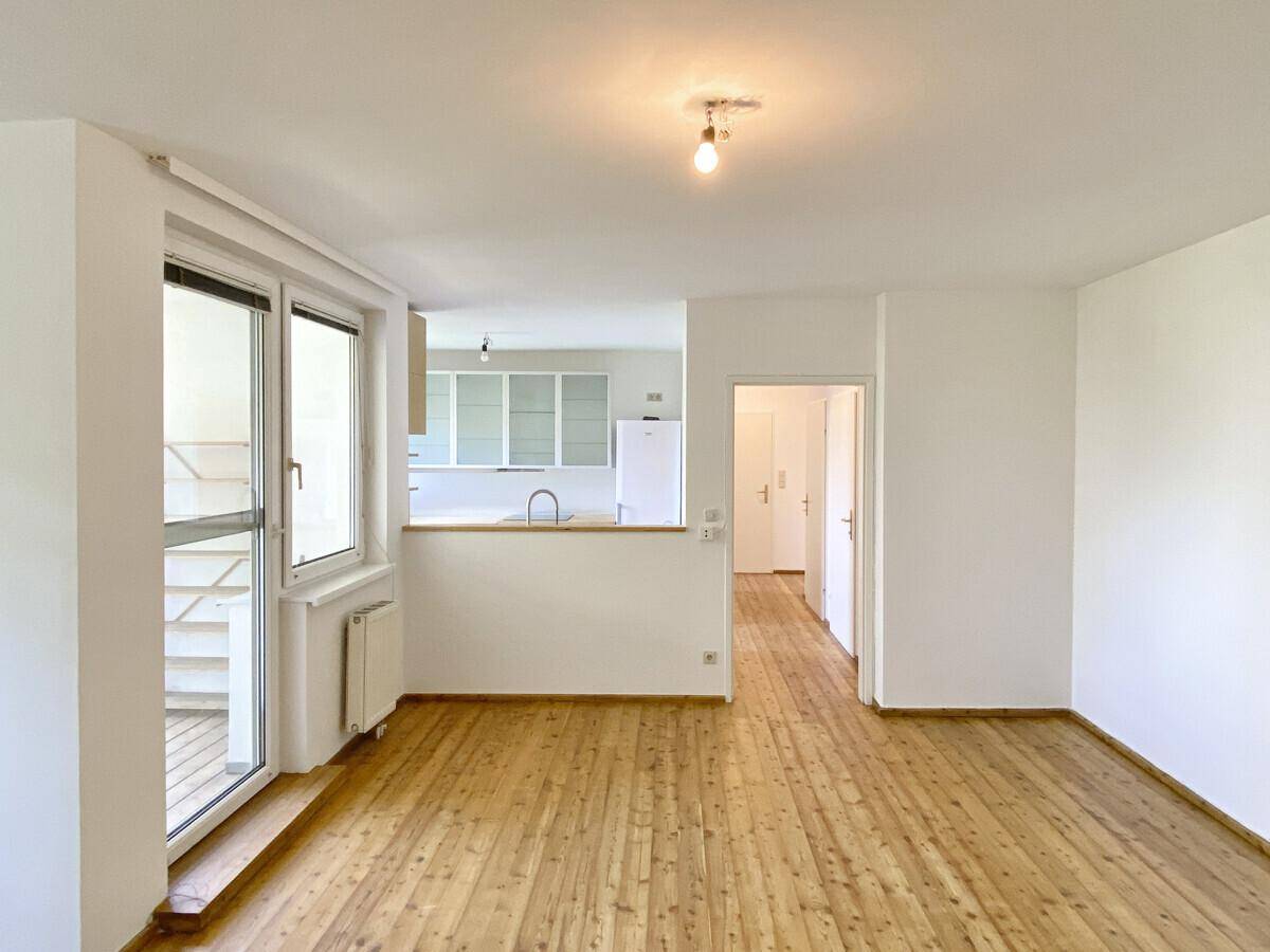 Offener Wohnbereich mit Holzboden und Blick auf die Küche, ideal für geselliges Beisammensein.