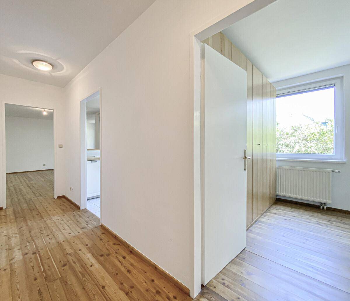 Heller Flur mit Holzboden, der zu den verschiedenen Zimmern der Wohnung führt.