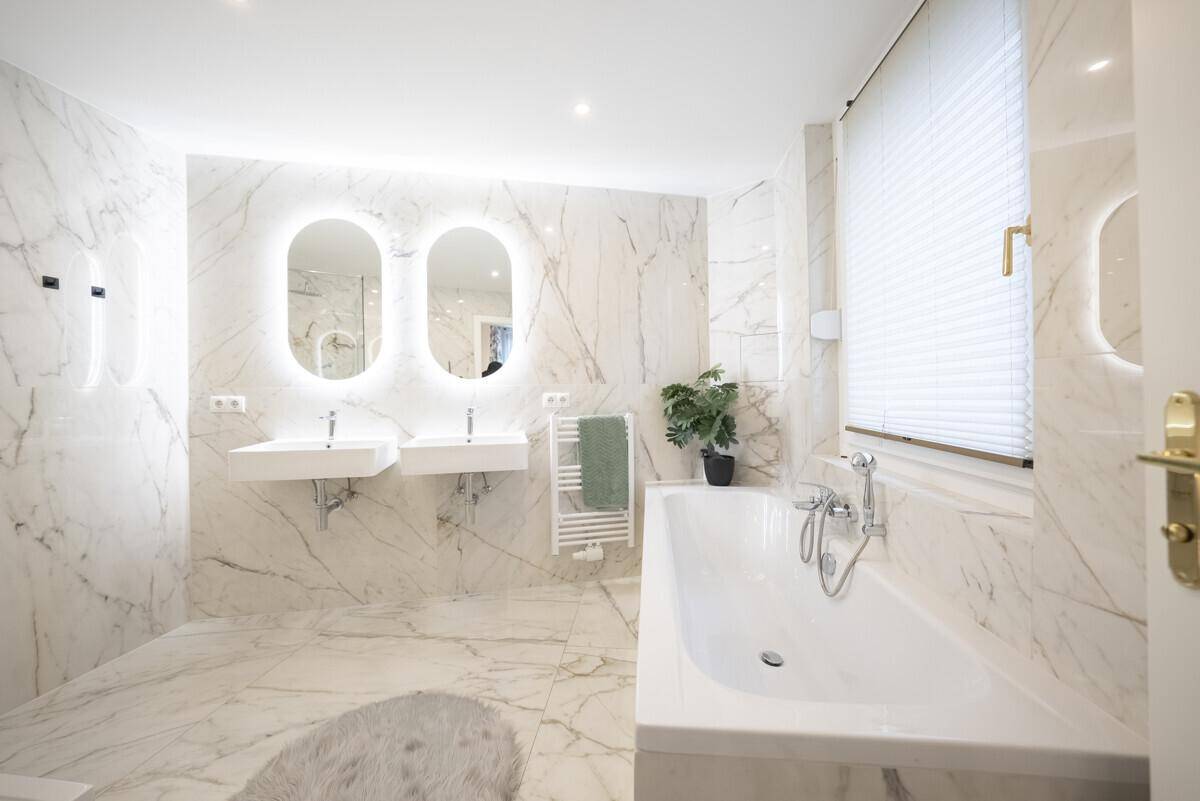 Luxuriöses Badezimmer mit Marmorfliesen, Doppelwaschbecken und integrierter Badewanne, sehr elegant.