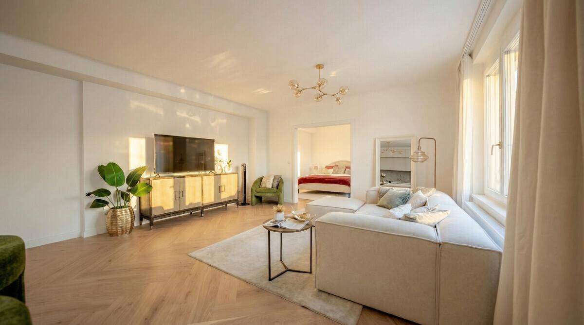 Gemütliches Wohnzimmer mit Sofa, Fernseher und Zugang zu einem weiteren Raum, hell und modern.