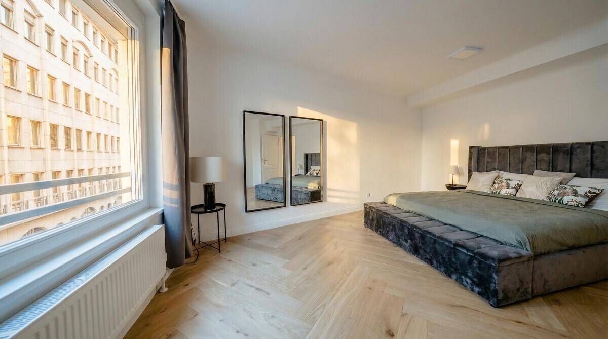 Helles Schlafzimmer mit Parkettboden, großem Fenster und modernem Interieur, sehr einladend.