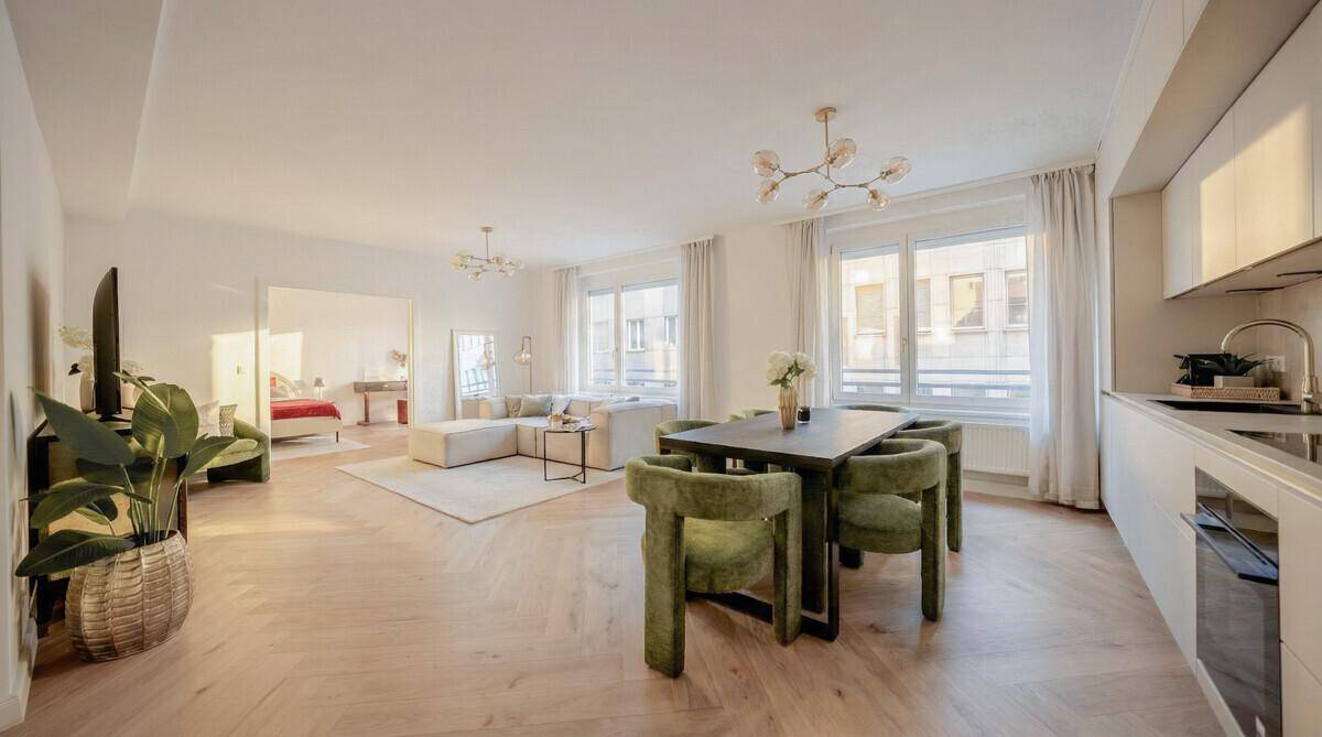 Geräumiger Wohn-Essbereich mit offener Küche und Blick in ein angrenzendes Schlafzimmer.