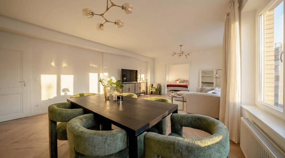 Eleganter Essbereich mit grünen Stühlen und Blick in den Wohn- und Schlafbereich, sehr offen gestaltet.