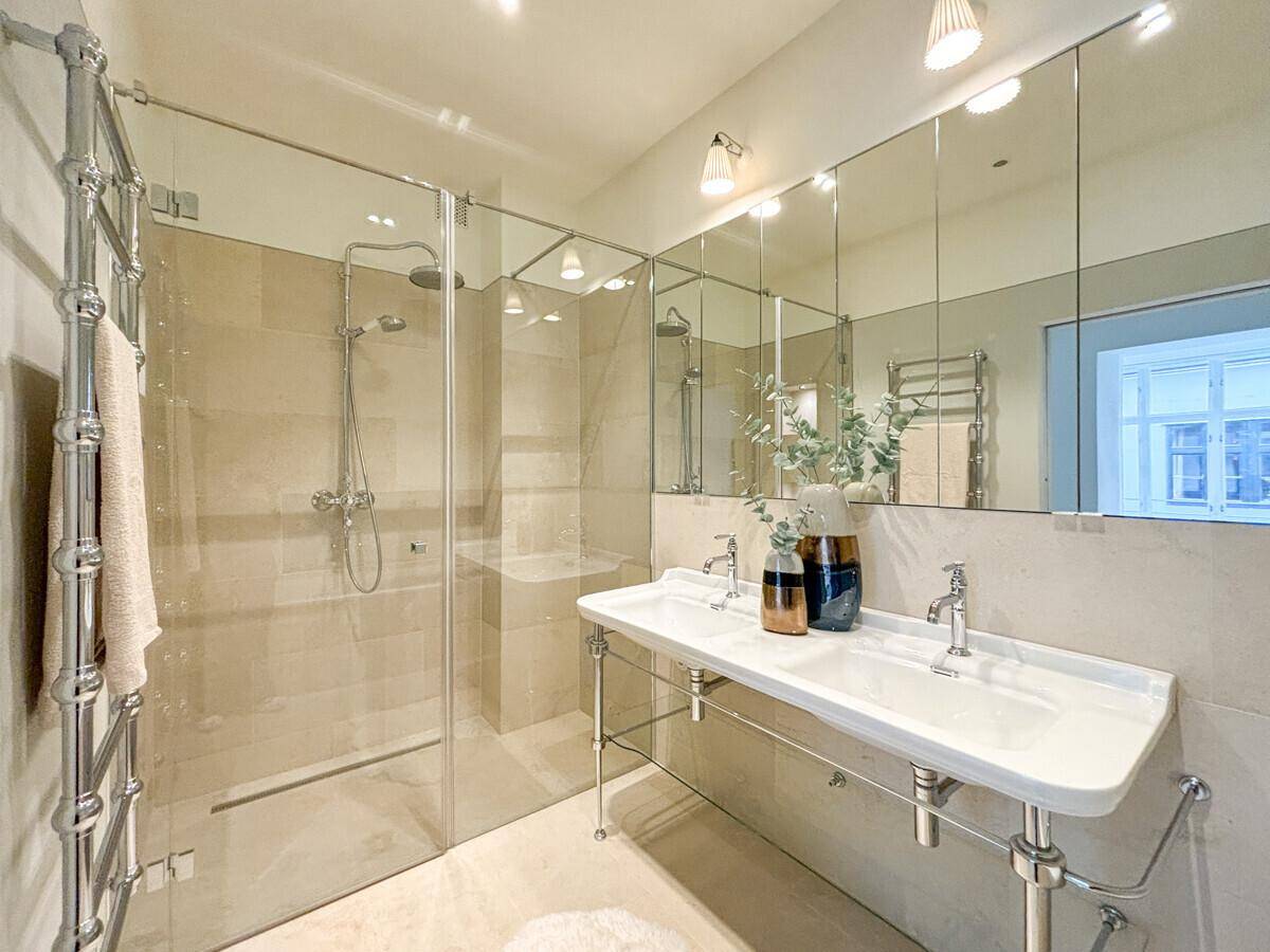 Modernes Badezimmer mit Doppelwaschbecken, großer Dusche und beheiztem Handtuchhalter für Komfort.