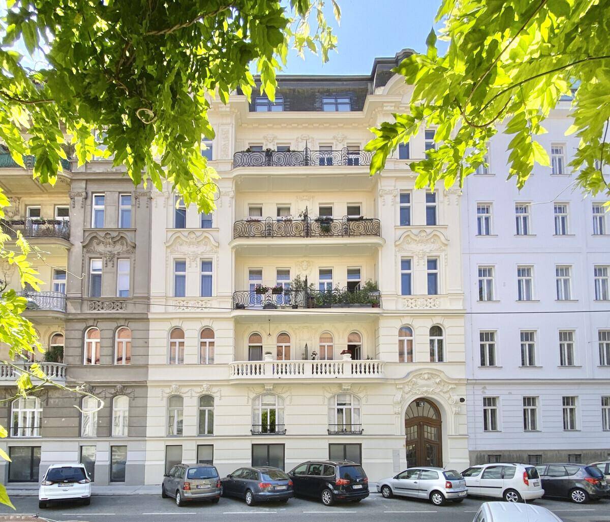 Historisches Wohngebäude mit reich verzierter Fassade, mehreren Balkonen und großen Fenstern.