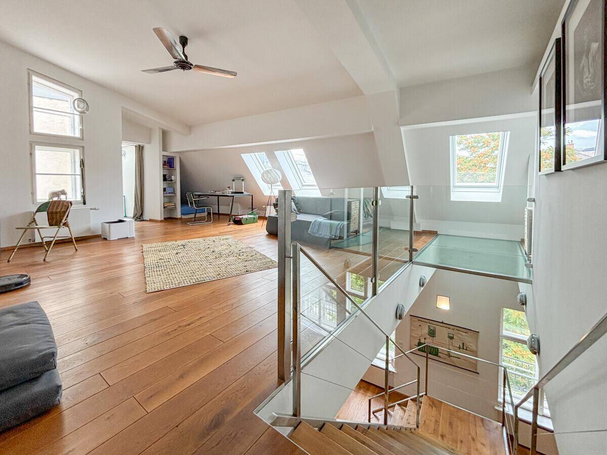 Heller Loftbereich mit Holzboden, Dachfenstern und Glasgeländer mit Blick auf die untere Etage.