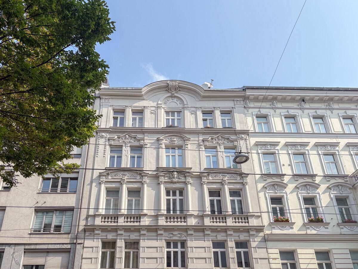 Historische Gebäudefassade mit reich verzierten Fenstern und Balkonen unter klarem blauem Himmel.