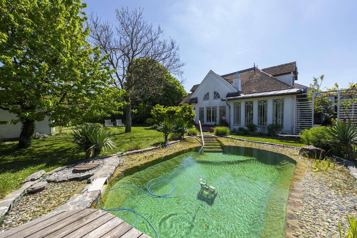 Großer Naturschwimmteich im weitläufigen Garten hinter dem charmanten Einfamilienhaus.