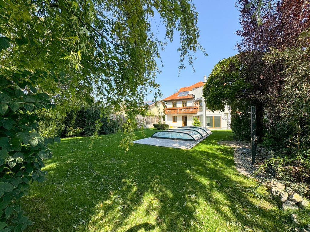 Idyllischer Garten mit üppigem Grün, Rasenfläche und Blick auf das Haus mit Pool.