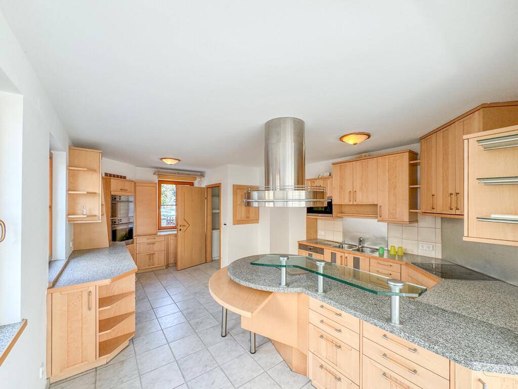 Geräumige Holzküche mit Granitarbeitsplatten, Kücheninsel und integrierten Geräten.