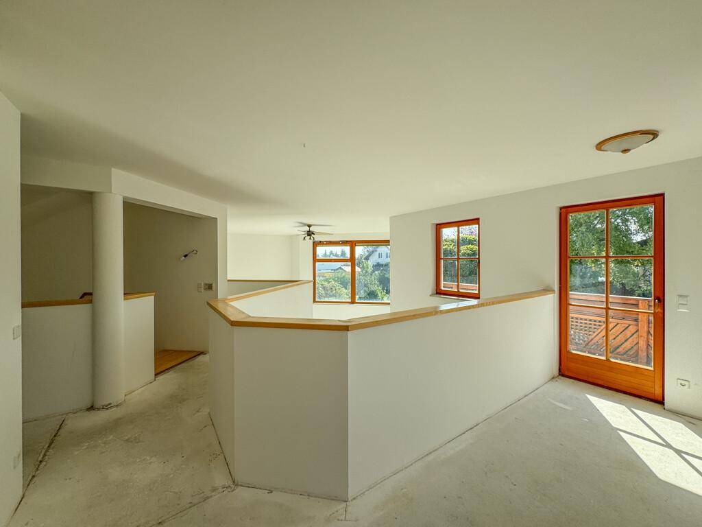 Heller Flurbereich im Obergeschoss mit Galerie und Zugang zu einem Balkon.