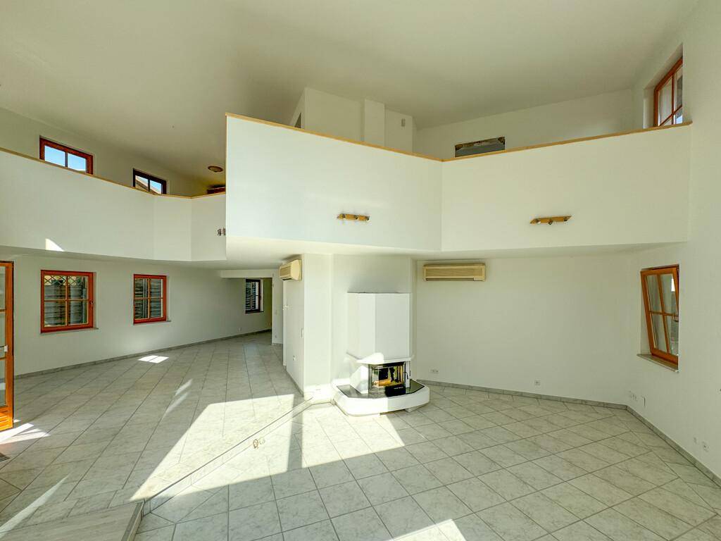 Offener Wohnbereich mit Kamin, hohen Decken und Galerie, ideal für großzügiges Wohnen.
