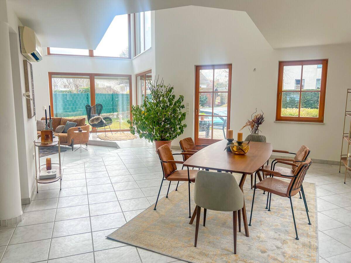 Heller Wohn- und Essbereich mit großen Fenstern, modernen Möbeln und Blick in den Garten.