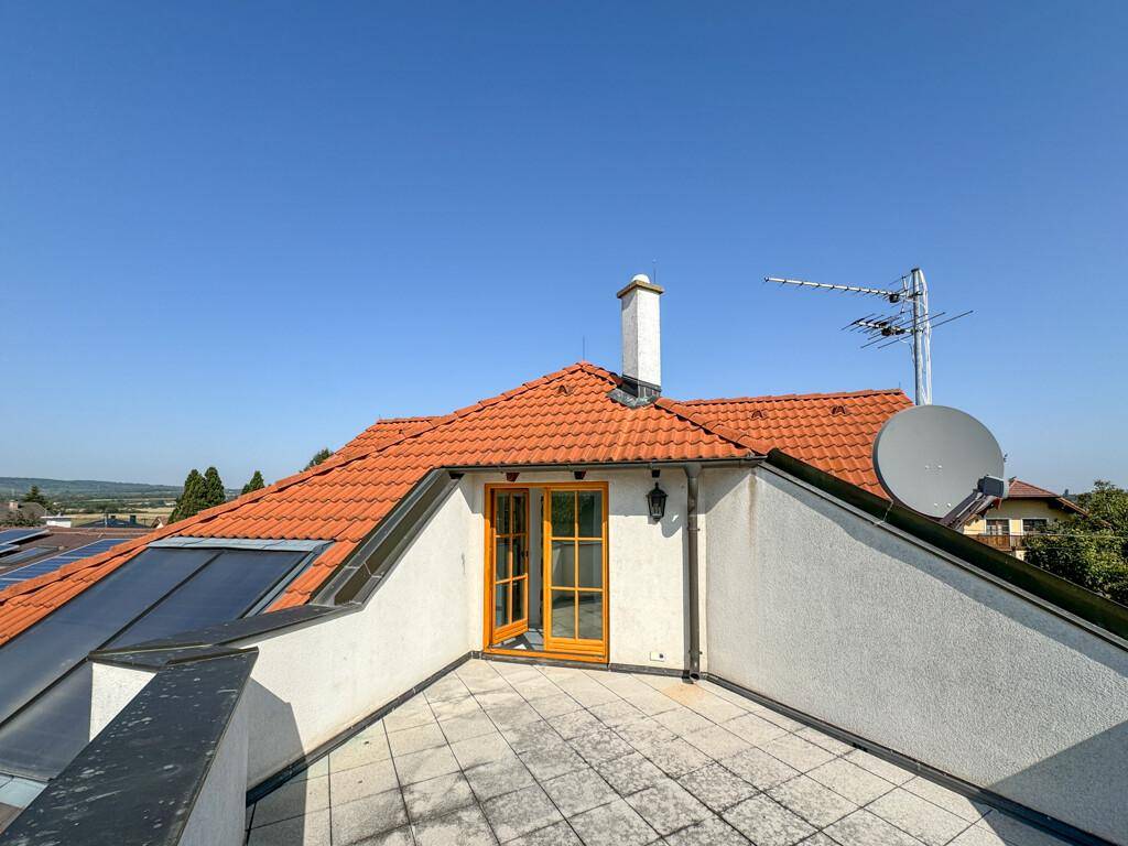 Dachterrasse mit Fliesenboden, Solarpaneelen und weitem Blick über die Umgebung.