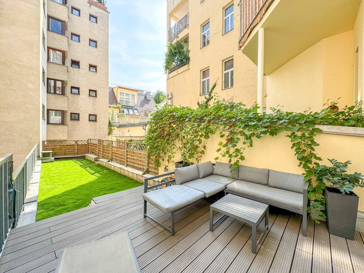 Moderne Terrasse mit Lounge-Möbeln und Kunstrasenfläche im Innenhof.
