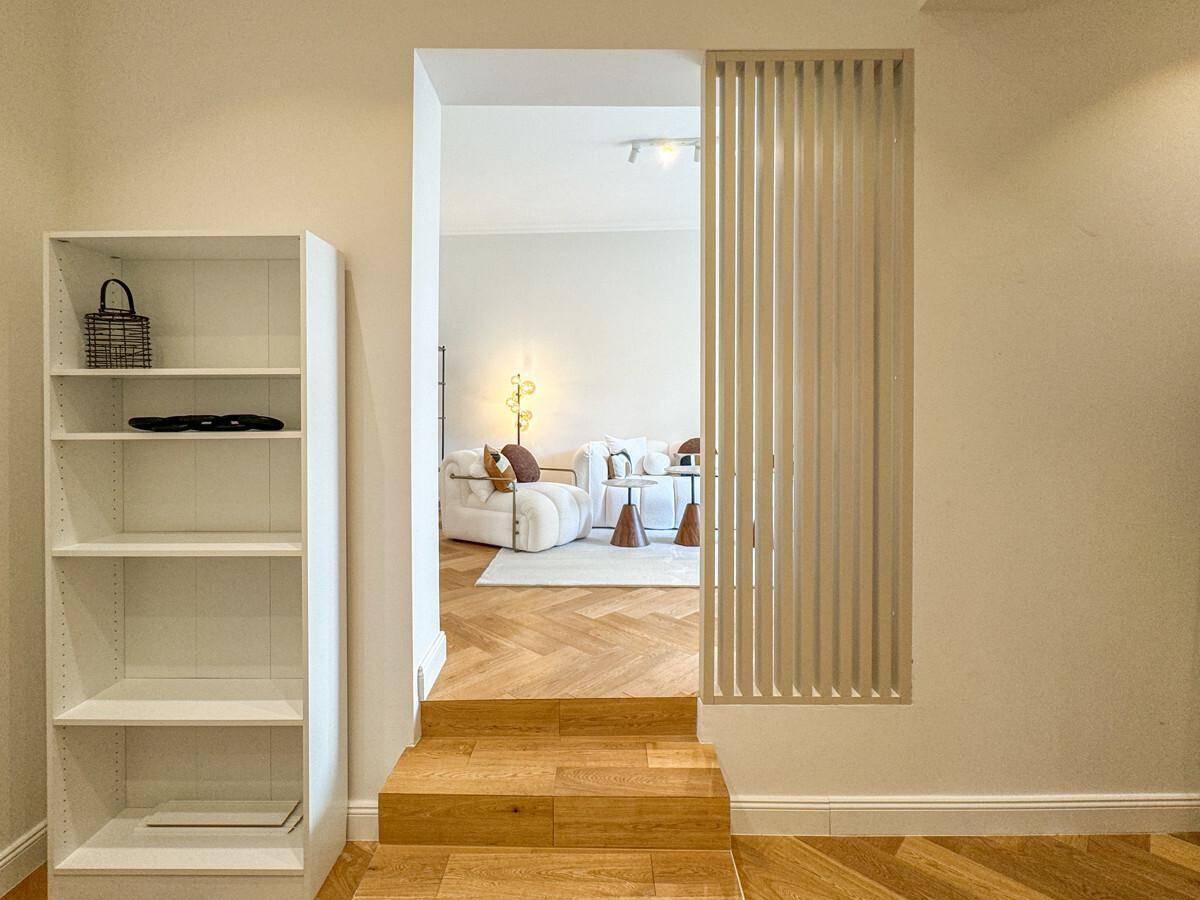 Heller Flurbereich mit Bücherregal und Blick in das angrenzende Wohnzimmer.