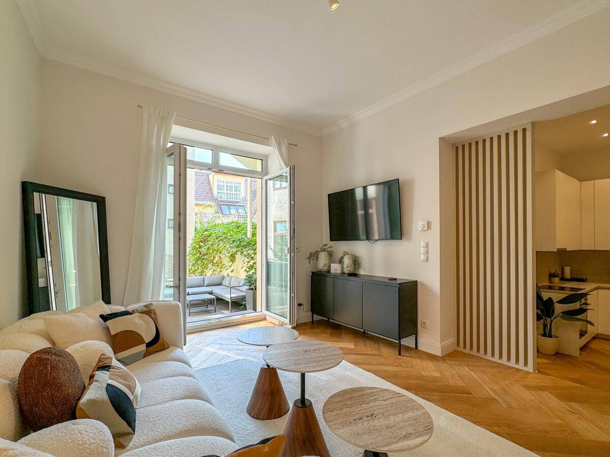 Gemütliches Wohnzimmer mit stilvollen Möbeln, Fernseher und Blick auf die Terrasse.