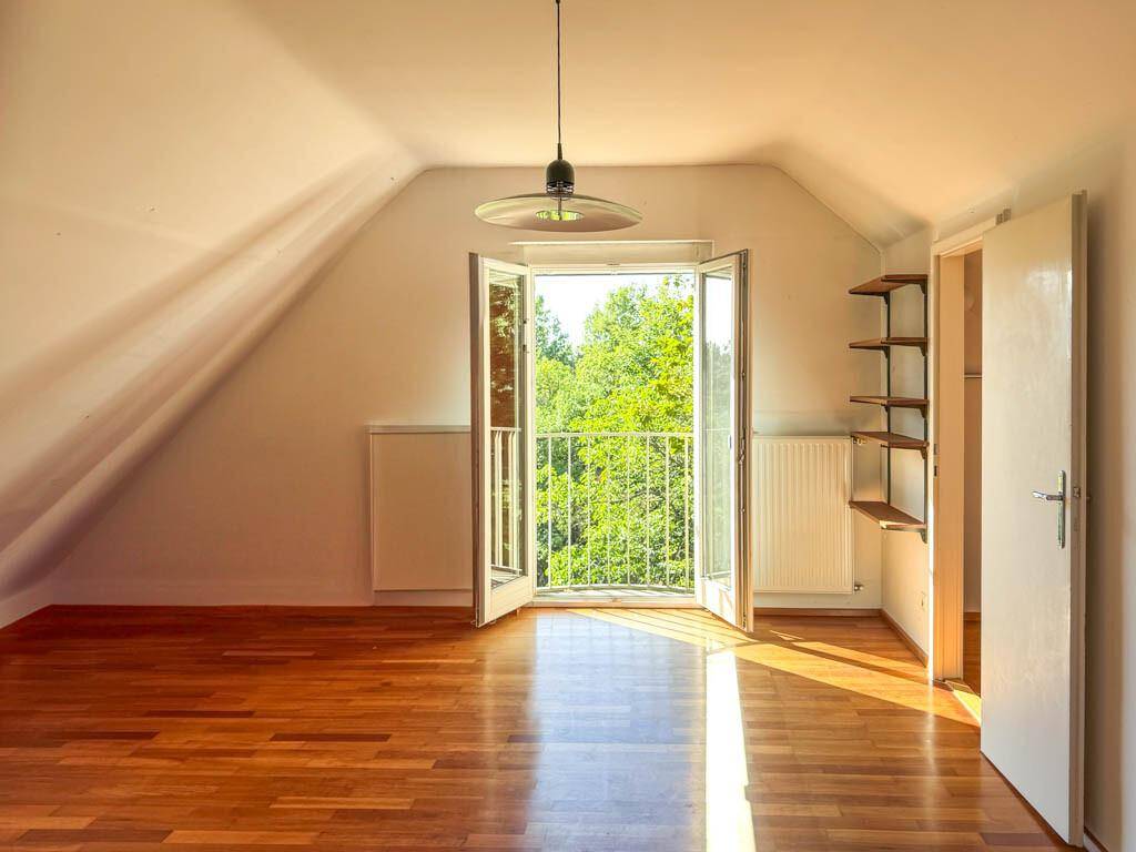 Helles Schlafzimmer im Dachgeschoss mit Holzboden, Dachschräge und französischem Balkon.
