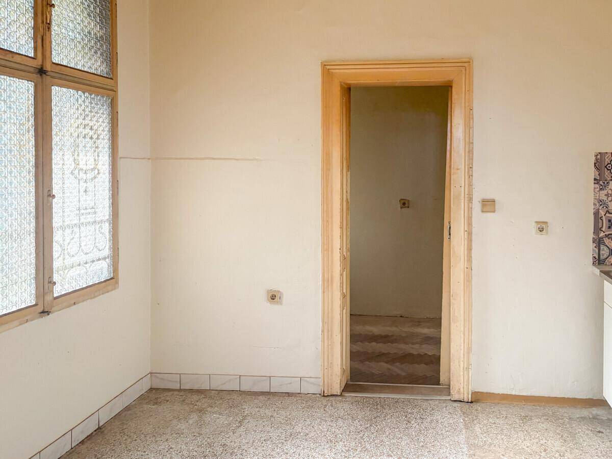 Leere Küche mit Fliesenboden, Fenster und vorbereitetem Bereich für die Küchenzeile.