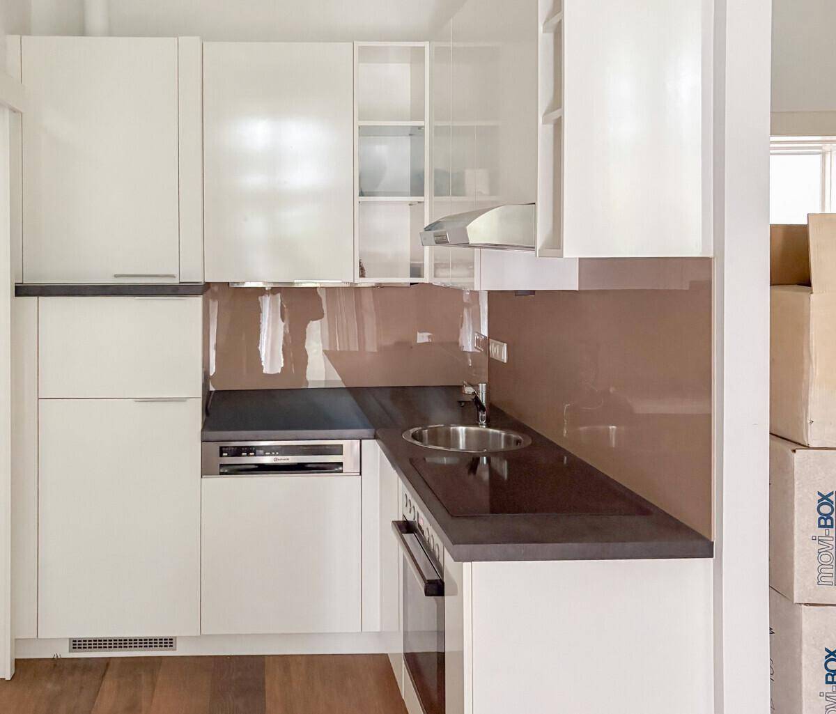 Moderne Einbauküche mit weißen Hochglanzfronten, dunkler Arbeitsplatte und integrierten Geräten.