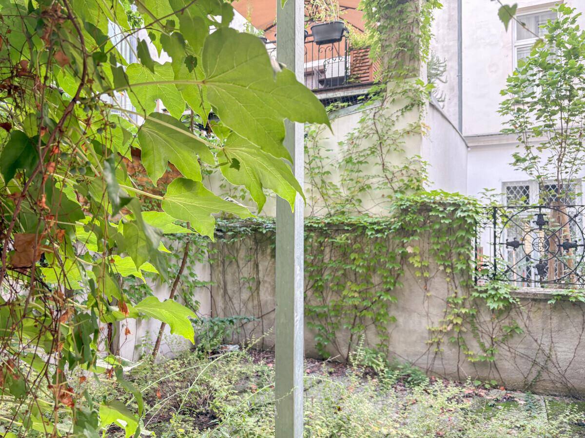 Grüner Innenhofgarten mit üppiger Bepflanzung und bewachsenen Mauern.